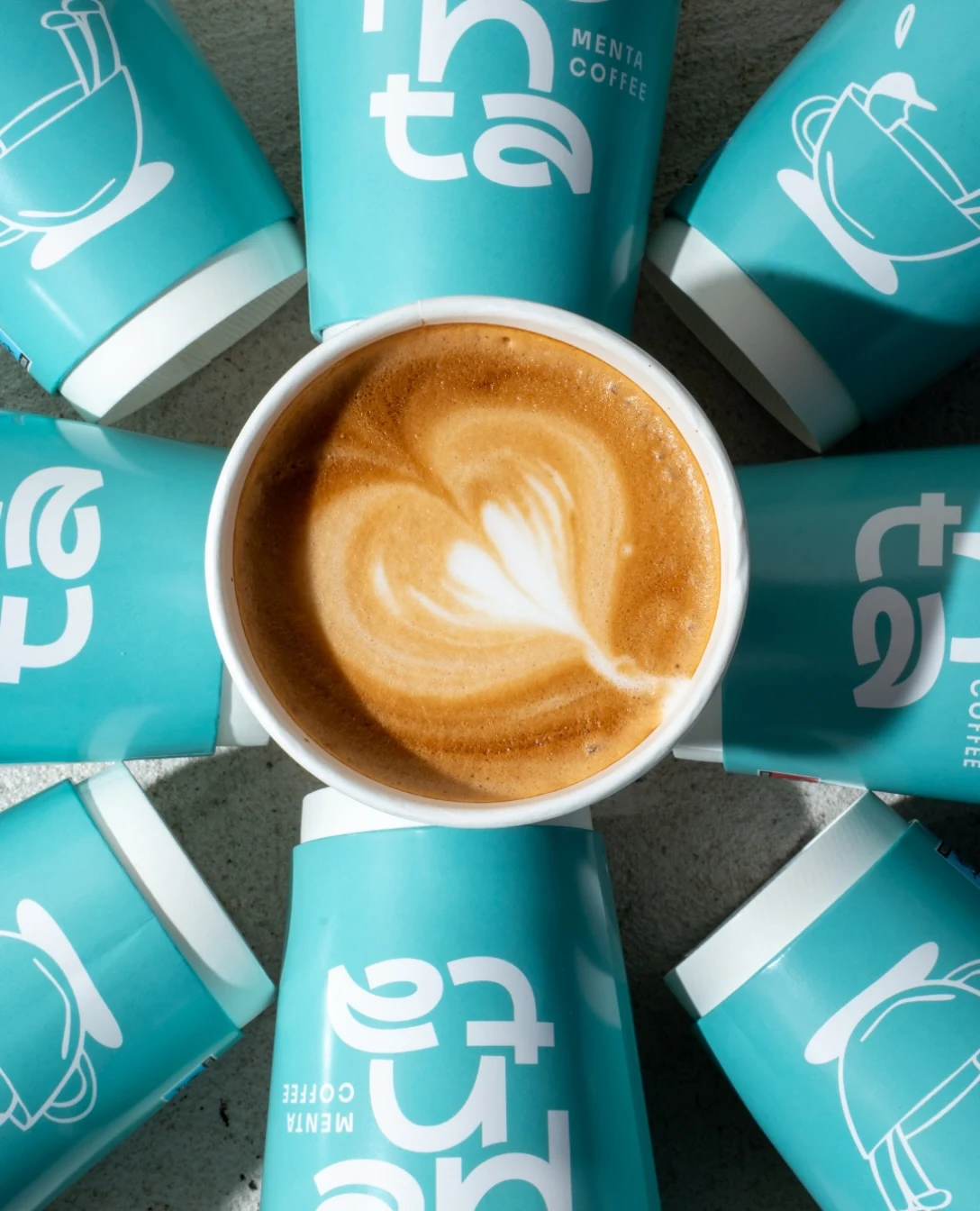 Latte art surrounded by turquoise MENTA cups