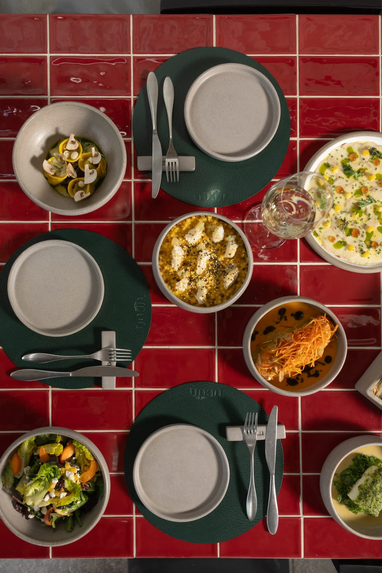 Mediterranean dishes arranged across a red tiled table at UPON